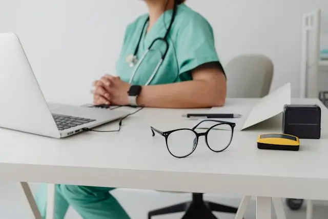 Doctor sitting at desk with laptop and stethoscope, showing a functional medicine consultation in Searcy, AR.